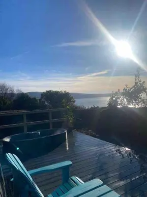 a deck with a bath tub and two chairs on it at Ocean View with hot tub in Barmouth