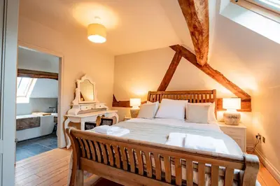 a bedroom with a large bed and a mirror at Oak Barn, Ludlow in Ludlow