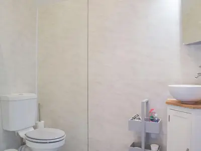 a white bathroom with a toilet and a sink at The Woodshed in Letton