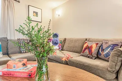a living room with a couch and a vase with flowers on a table at Ty Glyn Mansion Cottage in Ciliau-Aeron