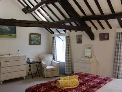 a bedroom with a bed and a dresser and a chair at Bryn Hyfryd in Harlech