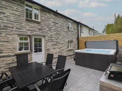 a patio with a hot tub and a table and chairs at Bwthyn Camlan in Machynlleth