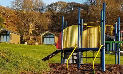 a playground with a slide in a park at Cabin Cynthia in Llwyngwril