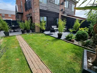 a backyard with a lawn with plants and tables and chairs at 1-Bed Apartment - Sleeps 2 & Private Parking in Llansantffraid-ym-Mechain