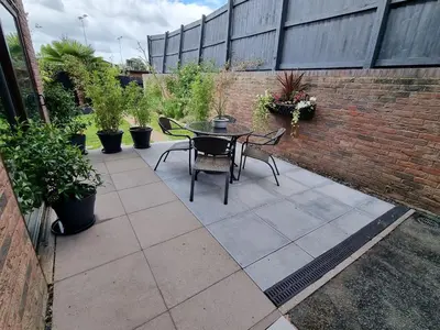 a patio with a table and chairs and a brick wall at 1-Bed Apartment - Sleeps 2 & Private Parking in Llansantffraid-ym-Mechain