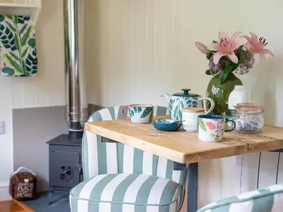 a table with cups and a vase with flowers on it at Collen in Llanarth