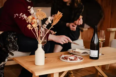 a table with a plate of food and a bottle of wine at The Bulls Head Wild Cabins in Hereford