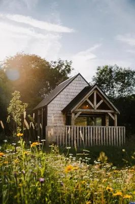 a barn with a fence and a field of flowers at The Bulls Head Wild Cabins in Hereford