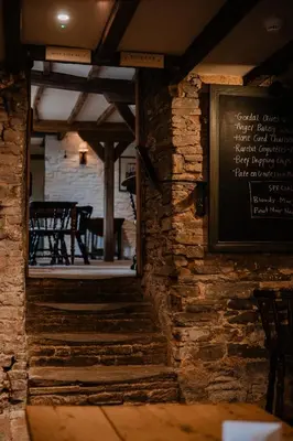 a restaurant with a stone wall with a chalkboard at The Bulls Head Wild Cabins in Hereford