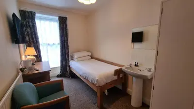 a small room with a bed and a sink at Morawel in Aberystwyth