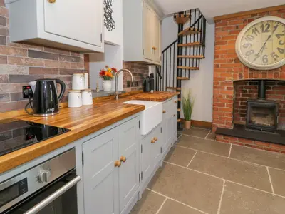 a kitchen with white cabinets and a brick wall at Y Bwthyn in Dolgellau