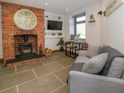 a living room with a brick fireplace with a clock at Y Bwthyn in Dolgellau