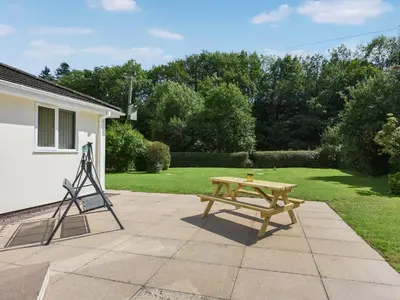 a wooden picnic table and a tripod next to a yard at The Bungalow in Castle Caereinion