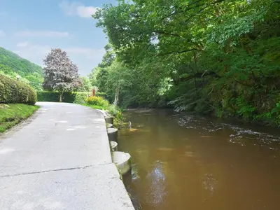 a river next to a walkway next to a road at The Bungalow in Castle Caereinion
