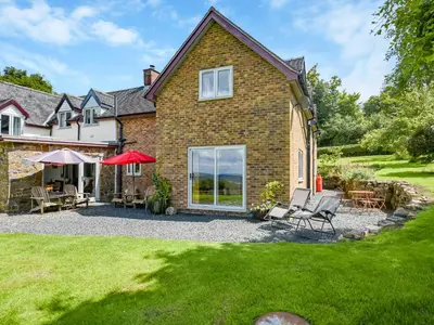a house with a patio and chairs in the yard at The Lodge At Harvest Farm in Ludlow
