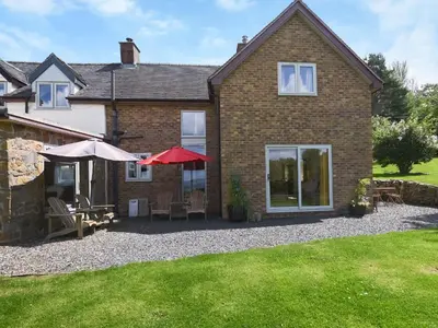 a house with a patio with tables and umbrellas at The Lodge At Harvest Farm in Ludlow