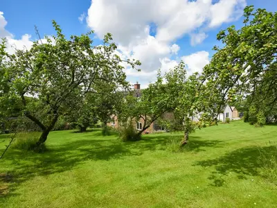 an apple orchard in front of a house with trees at The Lodge At Harvest Farm in Ludlow