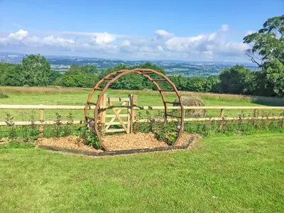 a garden in a field next to a fence at The Lodge At Harvest Farm in Ludlow