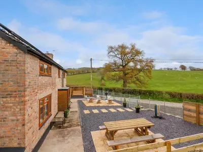 a patio with picnic tables and benches in front of a building at Aelybryn in Oswestry