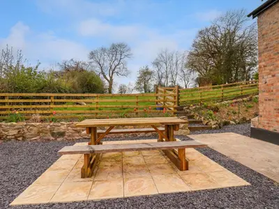 a wooden picnic table in front of a fence at Aelybryn in Oswestry