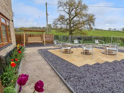 a patio with chairs and a bench and flowers at Aelybryn in Oswestry
