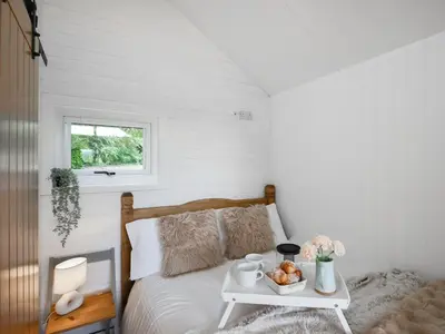 a bedroom with a bed and a table with a tray of food at Mini Lodge - Uk47682 in Montgomery