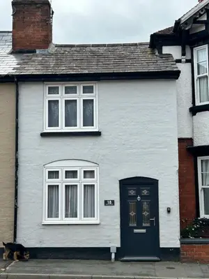 a white house with a dog sitting in front of it at Cottage in Ludlow in Ludlow
