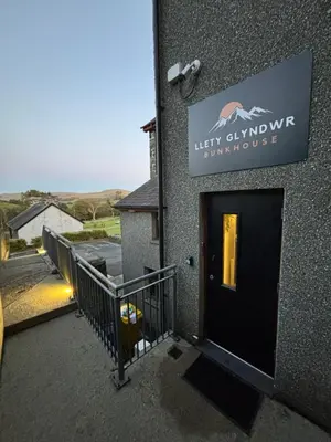a sign on the side of a building with a door at Llety Glyndwr - Bunkhouse in Trawsfynydd