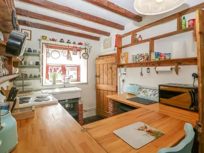 a kitchen with wooden counters and a wooden table at Violet Cottage in Llangammarch Wells