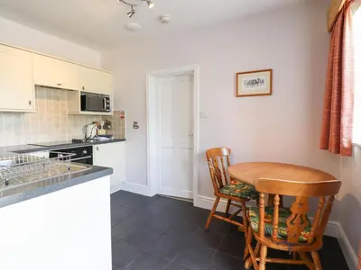 a kitchen with a wooden table and two chairs at Ty Llaeth Cottage in Tywyn