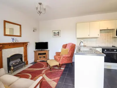 a kitchen with a living room with a fireplace at Ty Llaeth Cottage in Tywyn