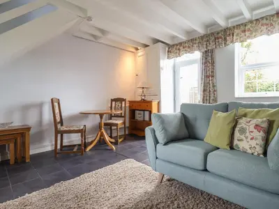 a living room with a blue couch and a table at Bwthyn y Gwas in Tywyn