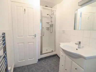 a white bathroom with a sink and a shower at Bwthyn y Gwas in Tywyn