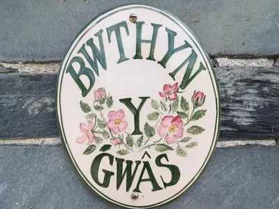 a sign that says winnie gymyss hanging on a wall at Bwthyn y Gwas in Tywyn