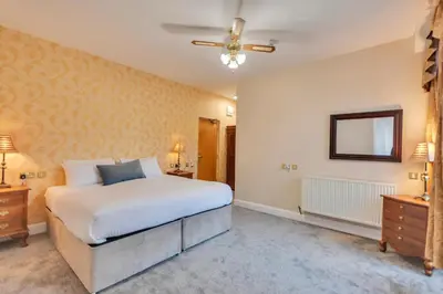 a bedroom with a large white bed and a mirror at White Waters Bed and Breakfast in Llangollen