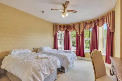 two beds in a bedroom with red curtains at White Waters Bed and Breakfast in Llangollen
