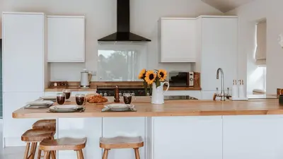 a kitchen with a wooden counter with chairs and flowers at The Old Dairy in Yarpole
