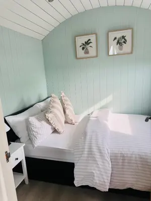 a bed with white pillows on it in a room at Bay View shepherds hut with hot tub in Llanfair