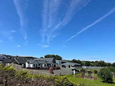 a row of houses in a parking lot with a blue sky at Derw View Green Lodge in Aberystwyth