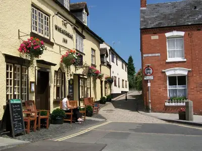 a man sitting at a table outside of a building at Frog Cottage, Ludlow - a charming townhouse for 4 in Ludlow