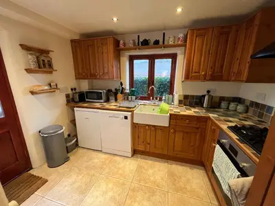 a kitchen with wooden cabinets and a sink and a window at Frog Cottage, Ludlow - a charming townhouse for 4 in Ludlow