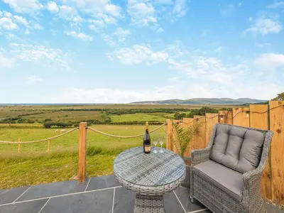 a table and a chair on a patio with a bottle of wine at Leri - Uk46065 in Llancynfelyn