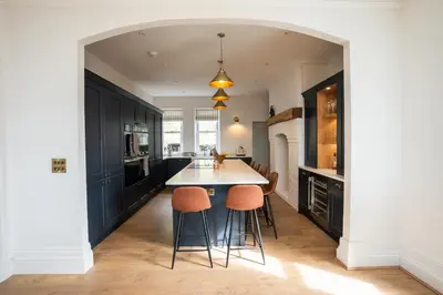 a kitchen with black cabinets and orange stools at Haulfryn in Barmouth