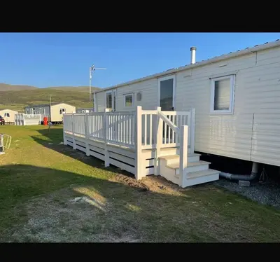 a white mobile home with a porch and stairs at Caravan in Barmouth in Llanddwywe