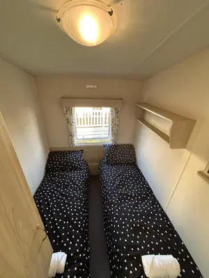 a small room with two beds and a window at Caravan in Barmouth in Llanddwywe