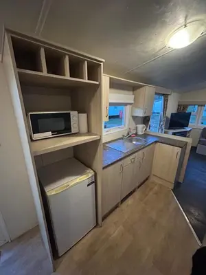 a small kitchen with a microwave and a sink at Caravan in Barmouth in Llanddwywe