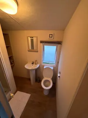 a small bathroom with a toilet and a sink at Caravan in Barmouth in Llanddwywe