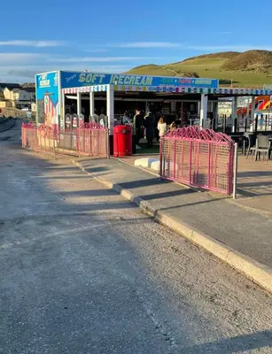 a store on the side of a road with red barriers at Lovley 3 bedroom Static Caravan in Clarach Bay in Aberystwyth