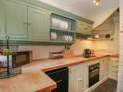 a kitchen with green cabinets and a counter top at Teacher's Cottage in Presteigne