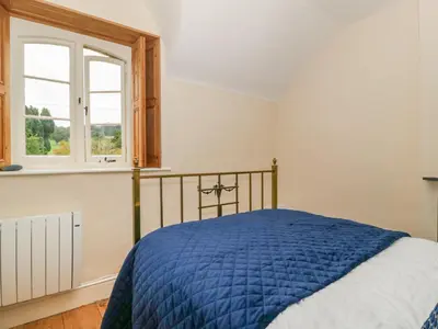 a bedroom with a bed and a window at Teacher's Cottage in Presteigne